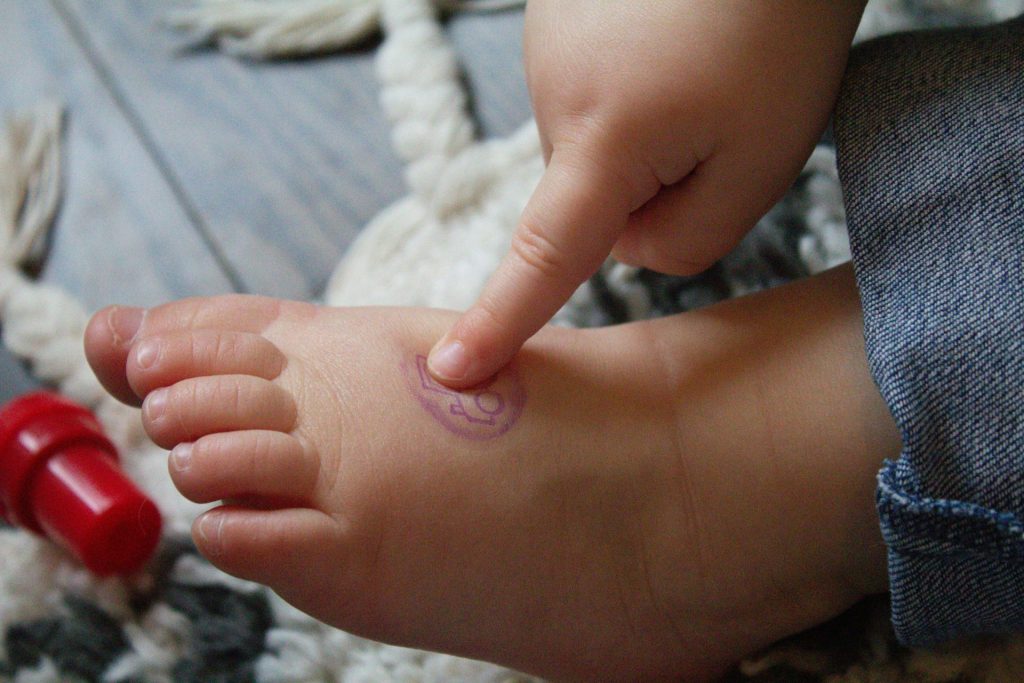 a small child's foot with a red object in the background
